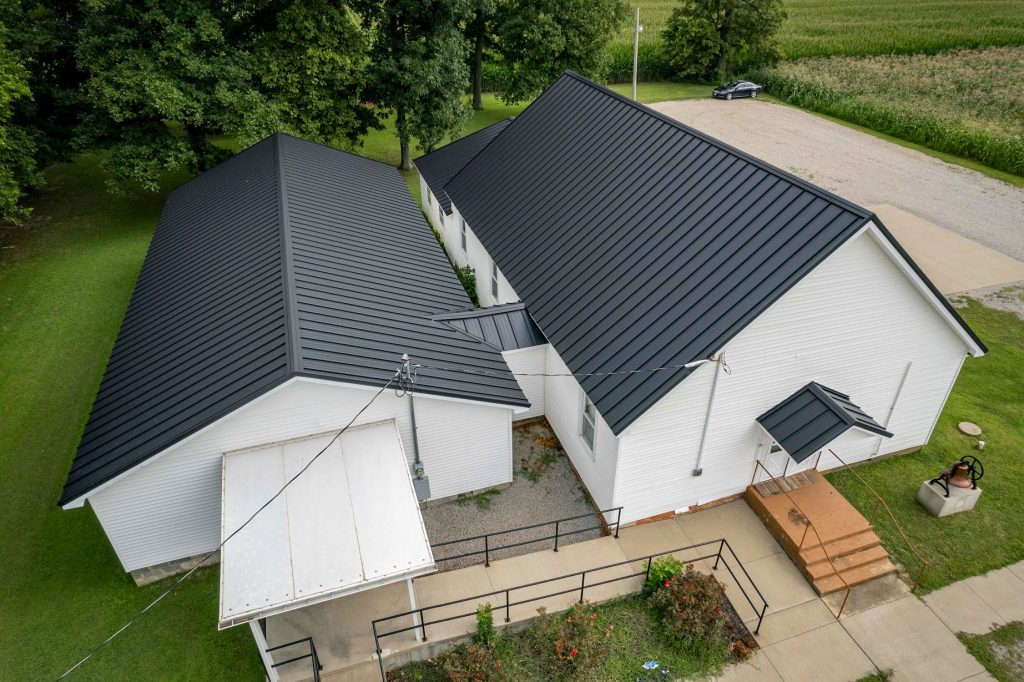 Bird's-eye view of a white church topped with a sleek black standing seam roof.
