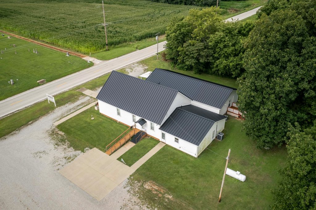 Aerial view of a church featuring a large driveway and a standing seam roof.