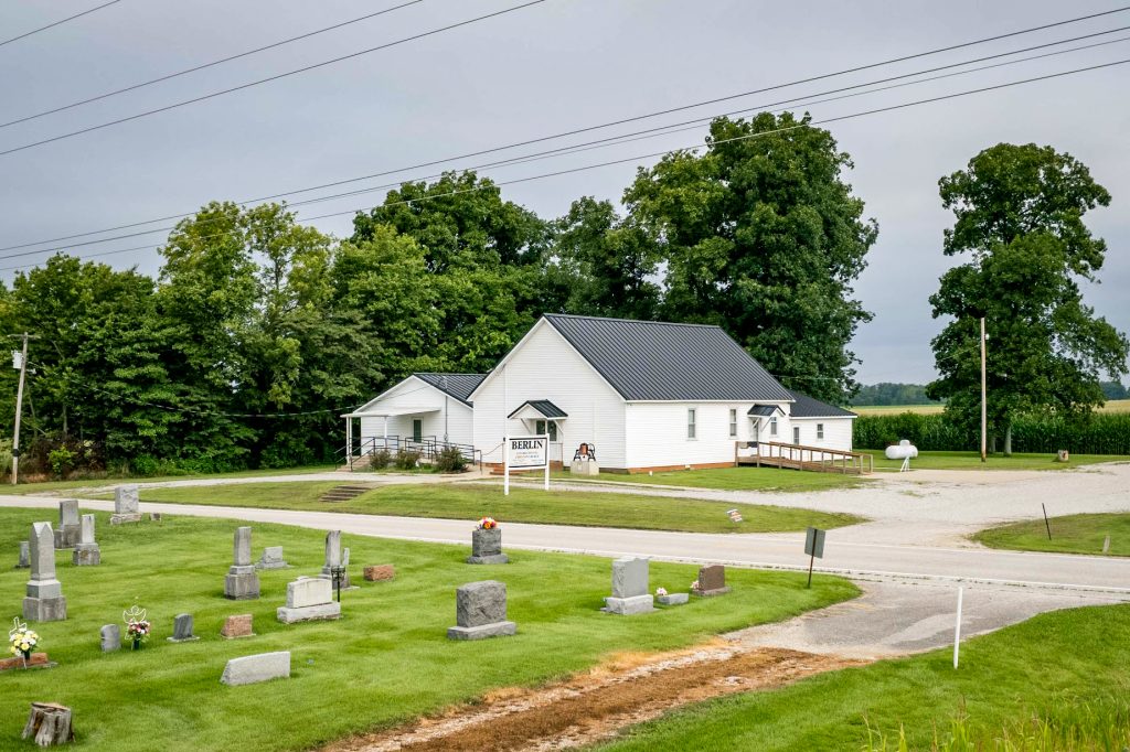 View of a church home featuring a large driveway and a standing seam roof.