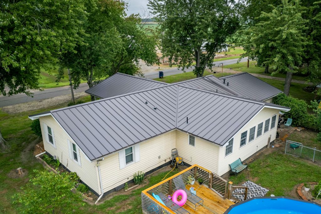 A house with a sleek standing seam metal roof and a refreshing pool, creating a stylish and relaxing atmosphere.