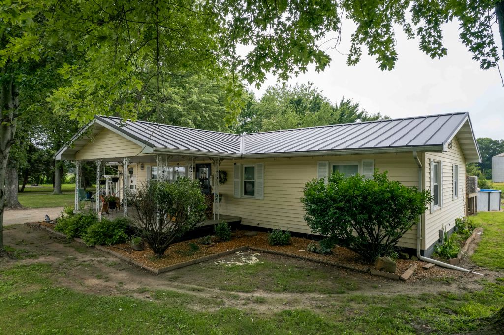 A small house featuring a standing seam metal roof and a welcoming porch.