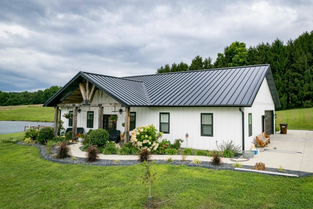A home with a standing seam metal roof, white siding, and a spacious yard.