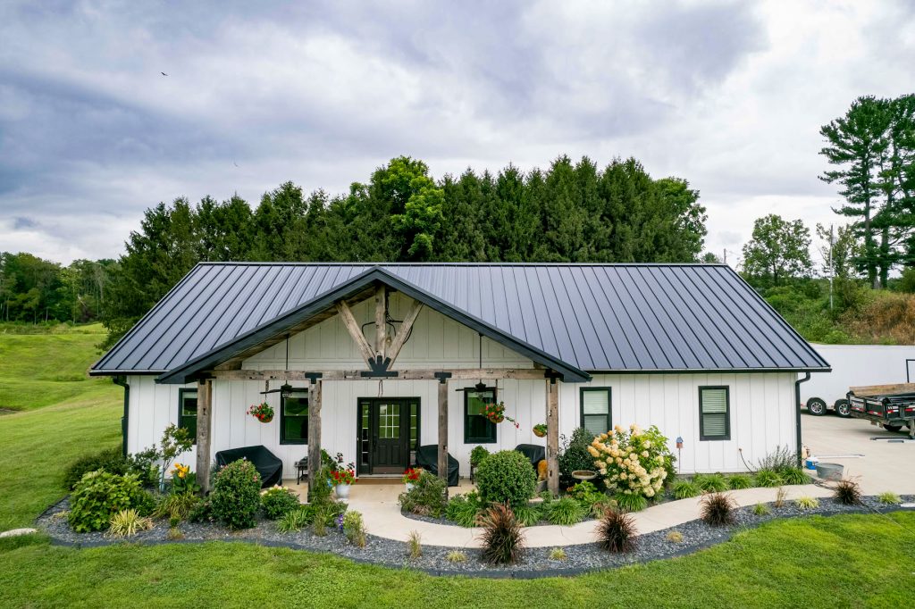 A white home featuring a sleek black metal standing seam roof, showcased in a photo gallery.