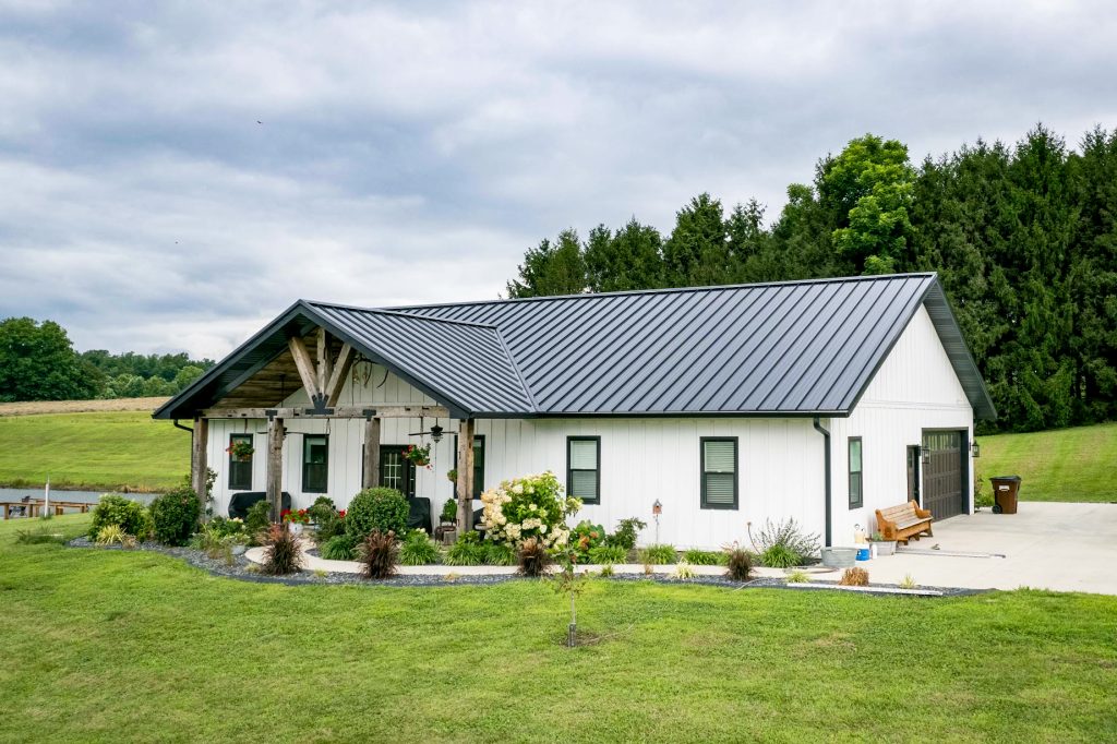 A house with, white siding and a black standing seam roof, complete with a garage.