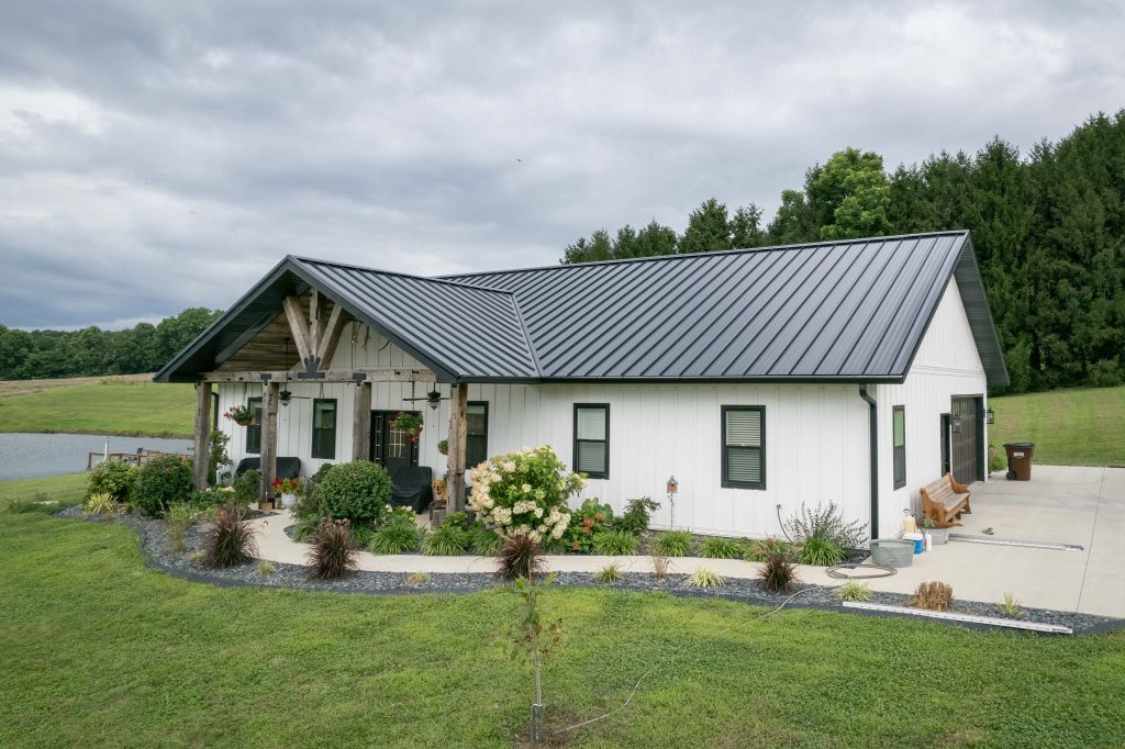 A home with a large porch featuring white metal siding and black metal standing seam roofing installed by Kingdom Home Exteriors in central Illinois.