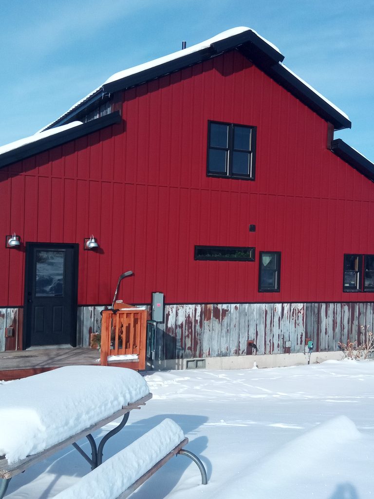 Barn with Rustic Red Crinkle metal siding and black metal trim set in winter snow scene