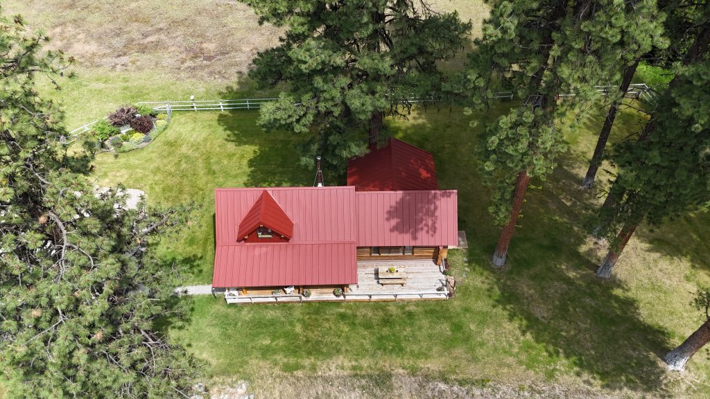Aerial view of cabin with Rustic Red Crinkle metal roof surrounded by ponderosa pine trees