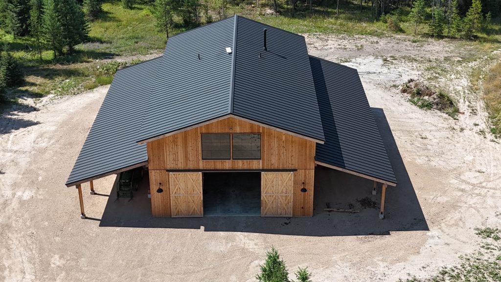 Aerial view of custom barn-style building with black standing seam metal roof and natural cedar wood accents