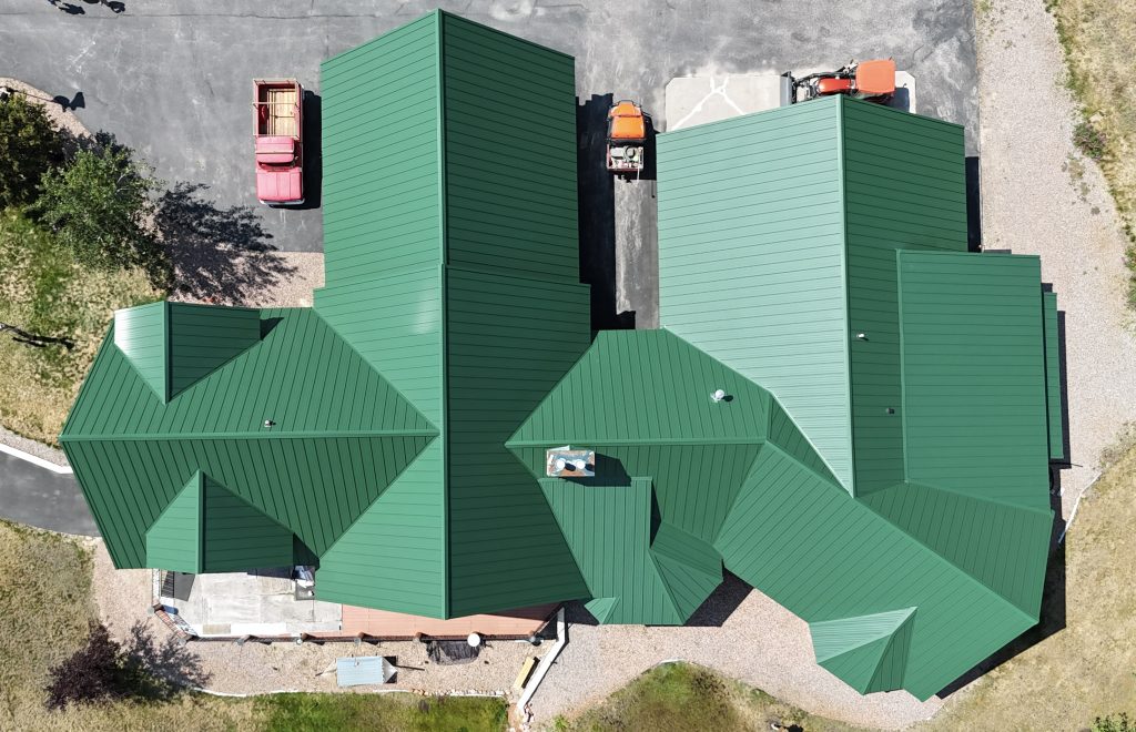 Overhead aerial view of complex multi-gabled green metal roof system with valleys and dormers