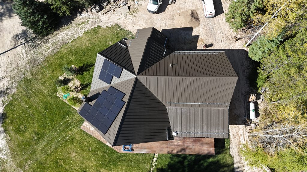 Aerial view of log home with charcoal metal roof and rooftop solar panel installation