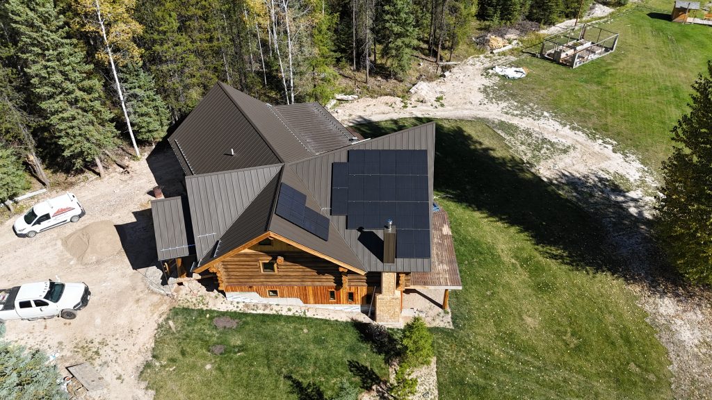 Log home with charcoal standing seam metal roof and extensive rooftop solar panel array
