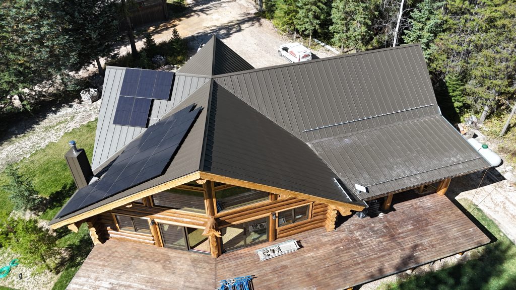 Overhead aerial of log home showing charcoal metal roof with integrated solar panel installation