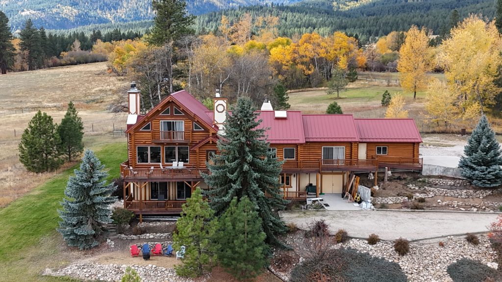 Aerial view of log home with Rustic Red metal roof surrounded by golden autumn aspens and pines