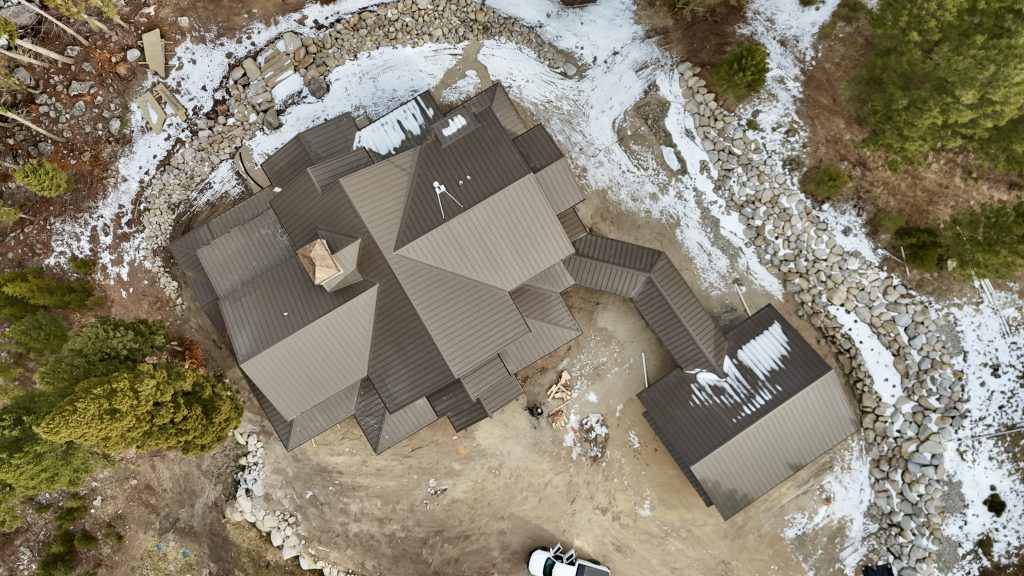 Overhead view of home with charcoal metal roof featuring complex multi-level design in winter snow