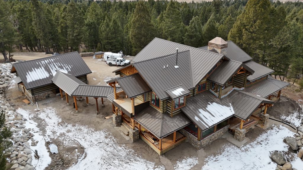 Aerial view of luxury log home with charcoal standing seam metal roof and covered walkways