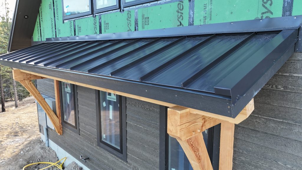 Detail view of standing seam metal porch roof with timber frame brackets and seamless gutter