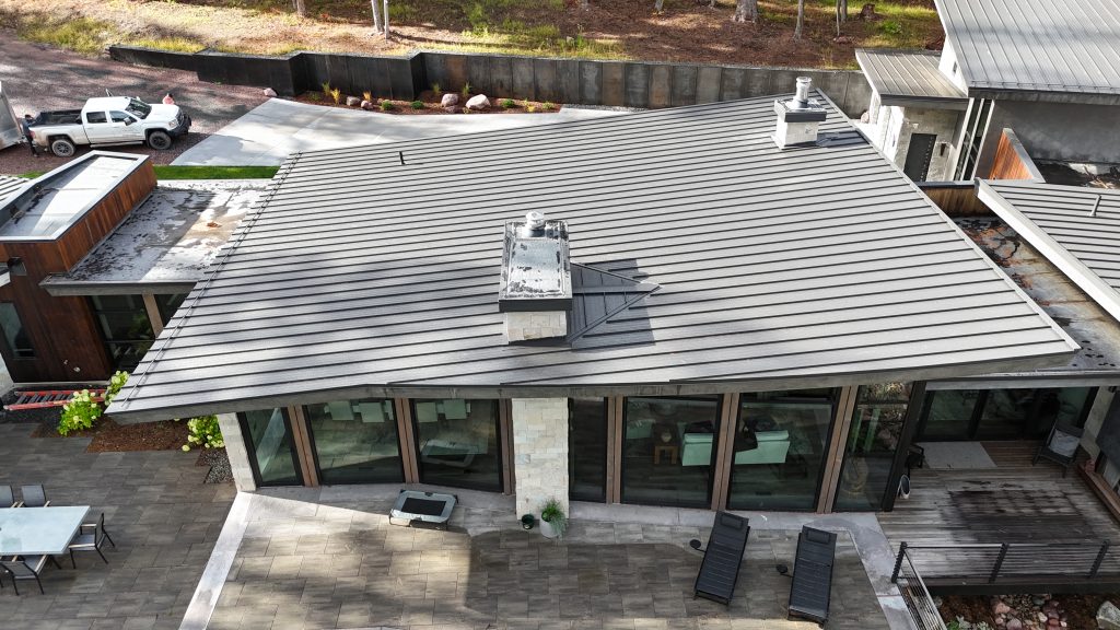 Close aerial view of charcoal standing seam metal roof on modern architectural home with cedar accents