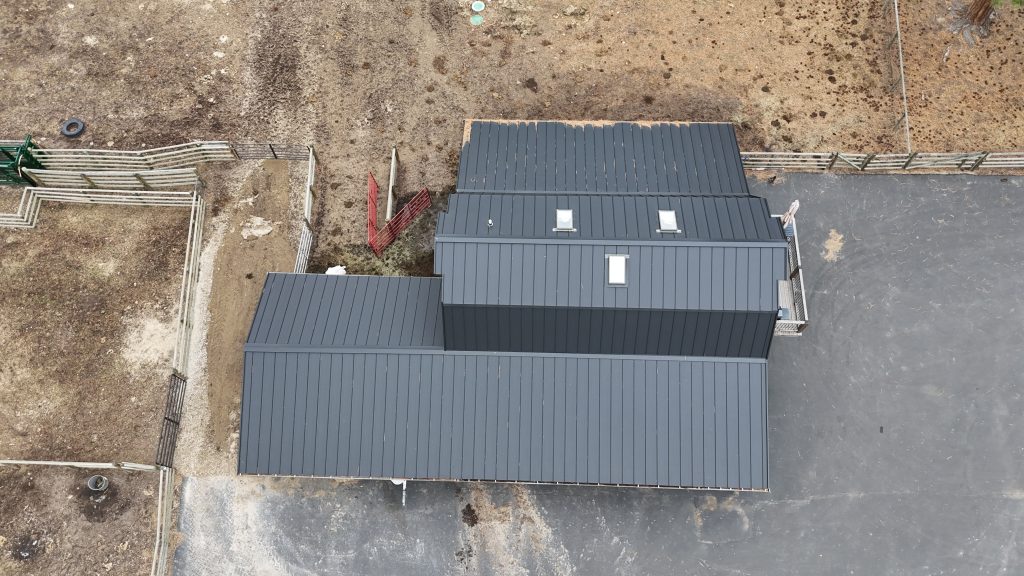 Overhead aerial of new accessory building with charcoal standing seam metal roof and skylights