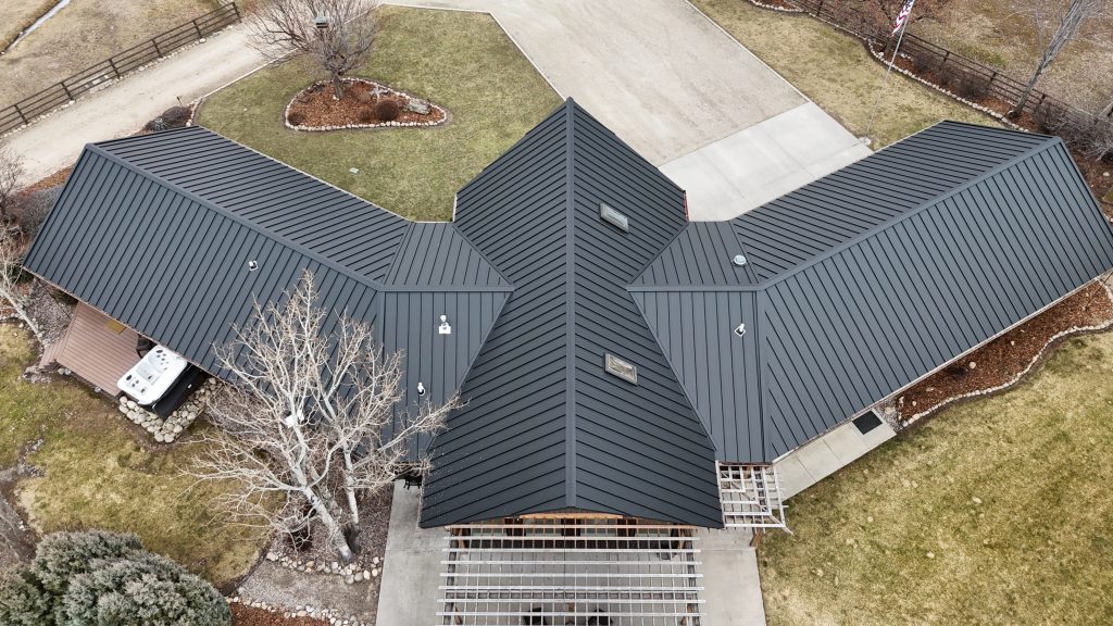 Overhead aerial of ranch home with charcoal metal roof and distinctive star-wing roofline