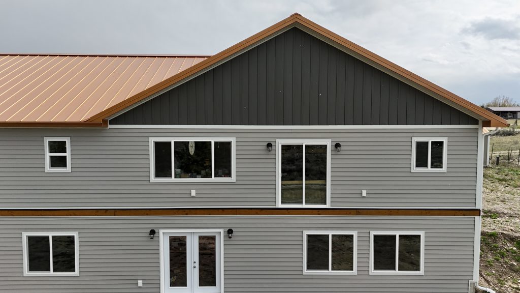 Close aerial of ranch home copper metal roof gable showing board and batten siding and panel detail